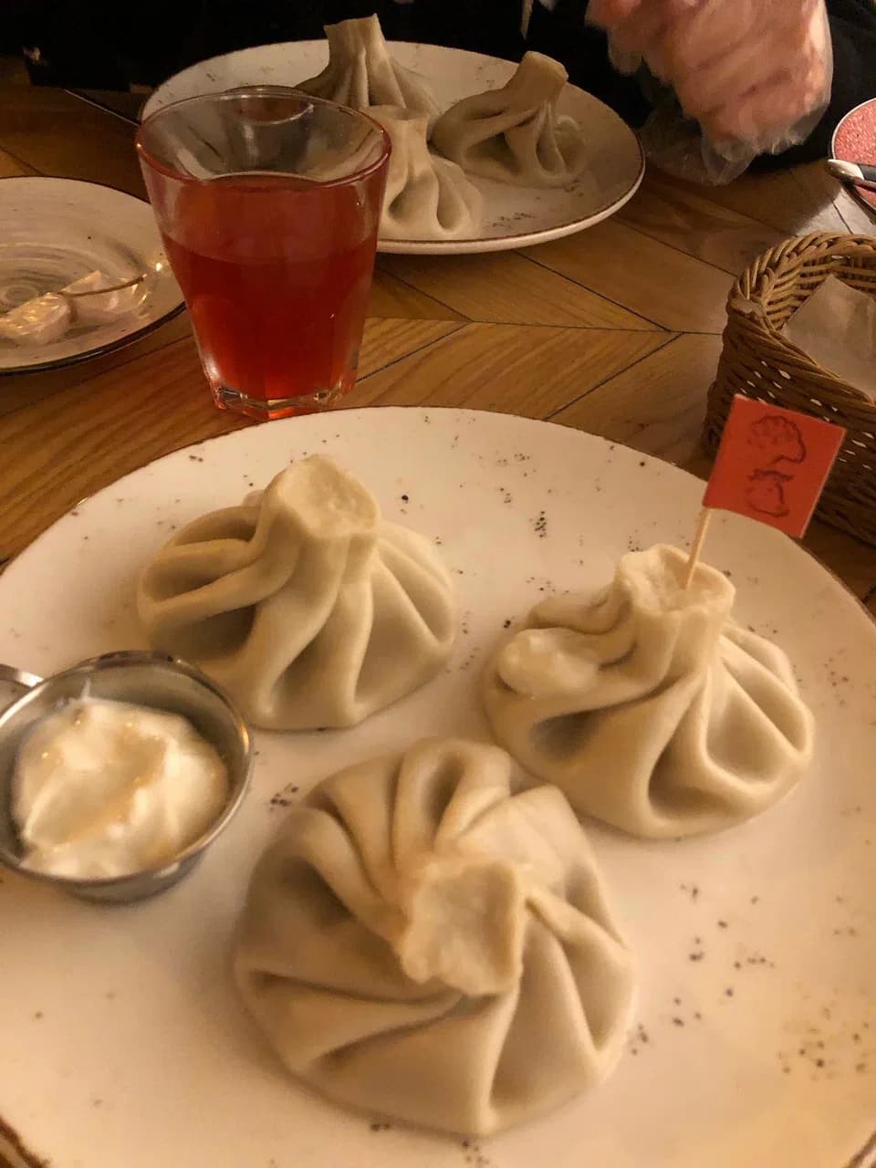 Хинкали ручной лепки на белой тарелке со сметаной