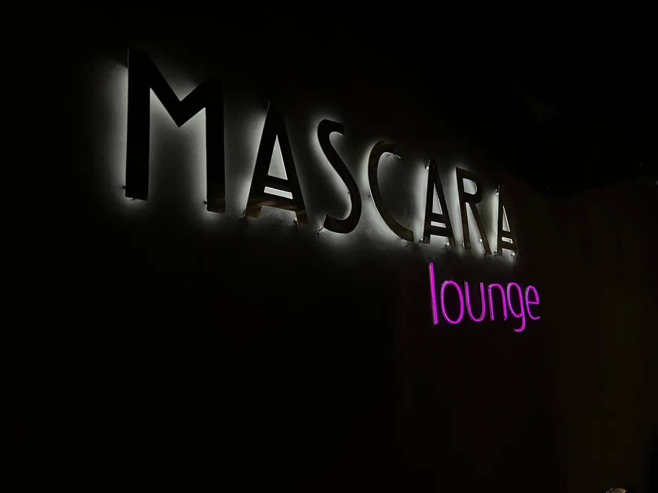 Подсвеченная вывеска Mascara lounge с розовой неоновой надписью в темноте